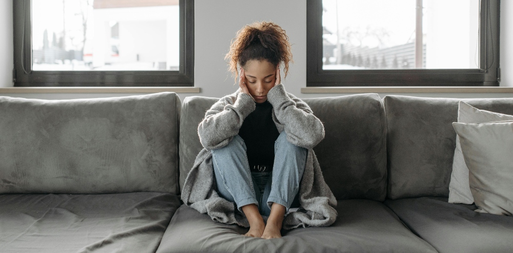 Woman sitting on couch worried that her Bulimia diagnosis needs treatment from We Conquer Together.